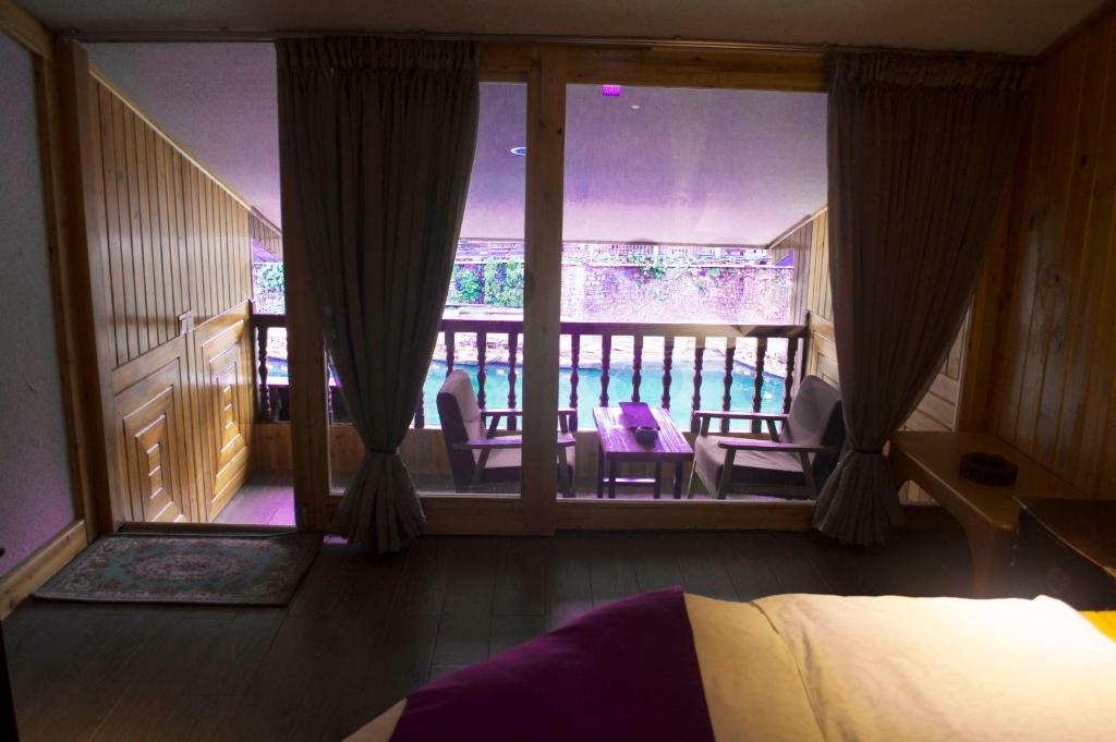 a bedroom with a balcony with a bed and chairs at Bian Cheng Xing Zi Inn in Fenghuang County