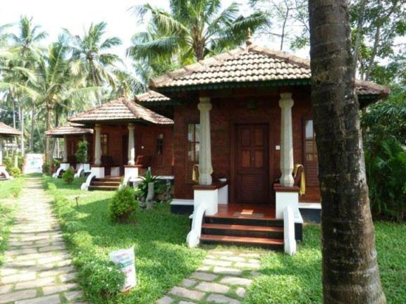 a small house in a yard with palm trees at Rajadhani 5th Season in Varkala