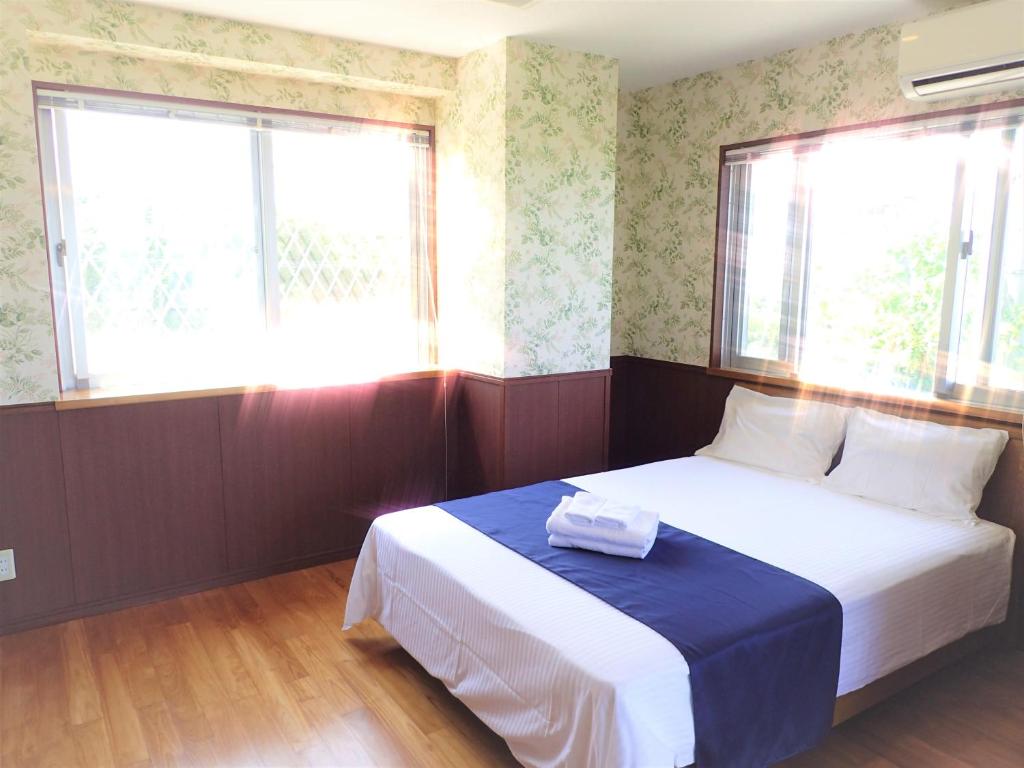 a small bedroom with a bed and two windows at Seaside KLATCH -Villa&sauna- in Ishigaki Island
