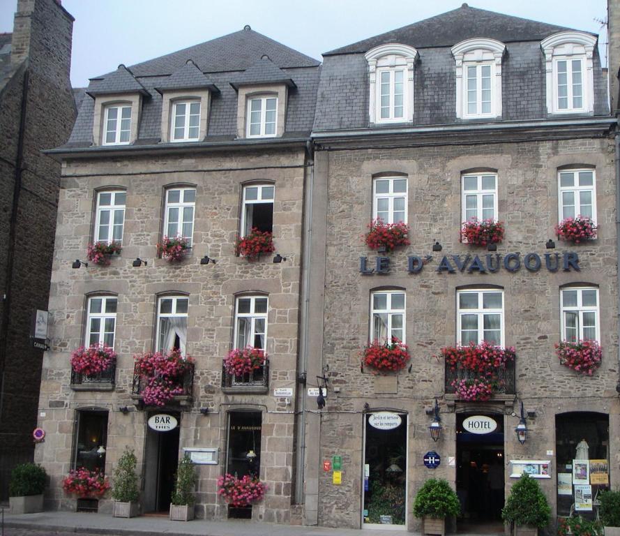 un vieux bâtiment en pierre avec des fleurs aux fenêtres dans l'établissement Hôtel Le D'Avaugour, à Dinan