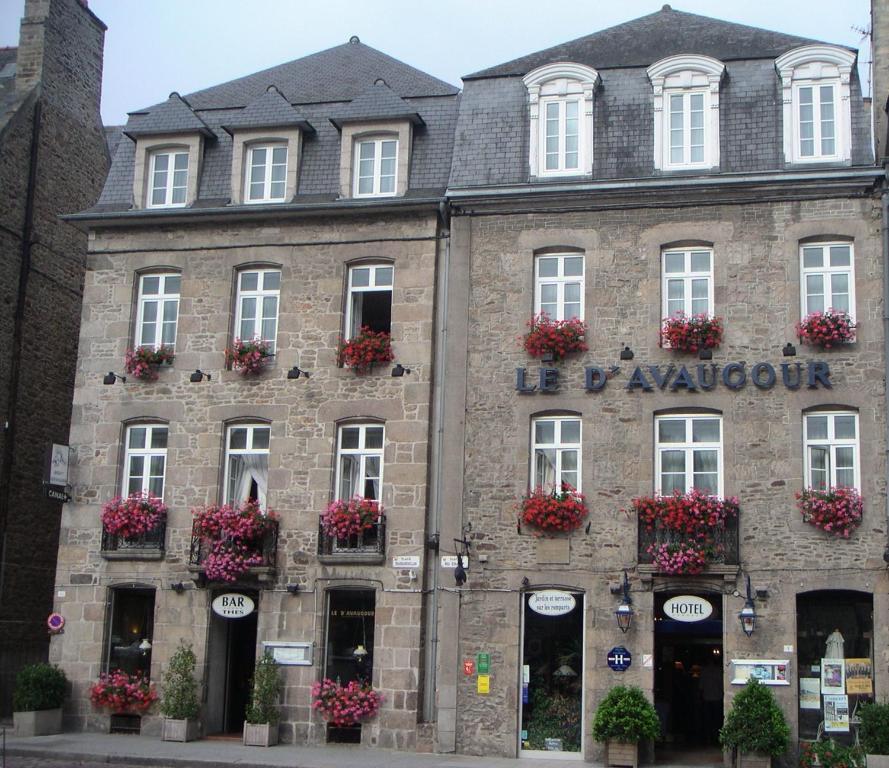 un antiguo edificio de piedra con flores en las ventanas en Hôtel Le D'Avaugour, en Dinan