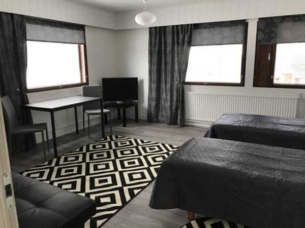 sypialnia z 2 łóżkami, stołem i oknami w obiekcie Guesthouse Julia w mieście Kajaani