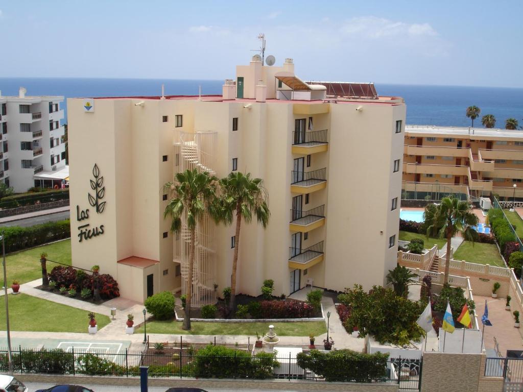 a large white building with palm trees next to the ocean at Los Ficus in Playa del Ingles
