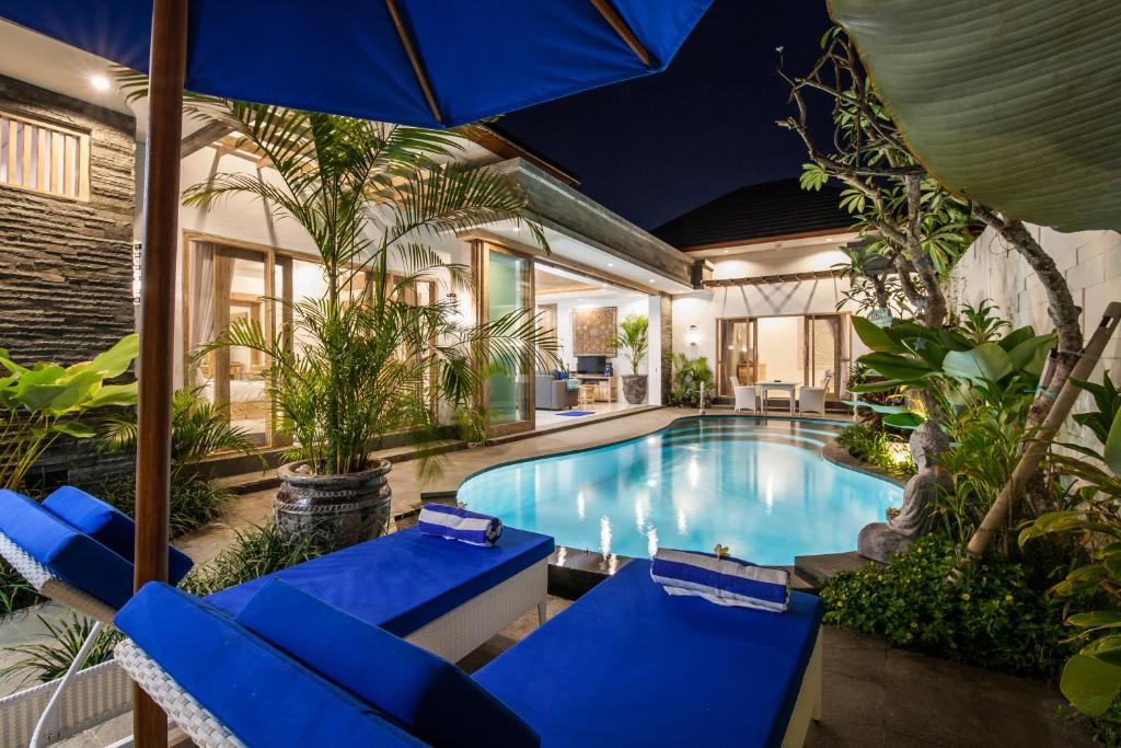 an indoor pool with blue chairs and an umbrella at Ambermoon Villas in Seminyak