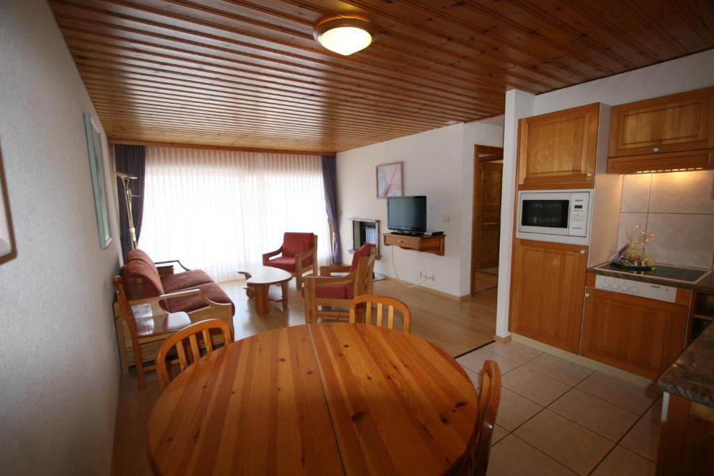 a kitchen and living room with a wooden table and chairs at Résidence Mont-Calme in Nendaz