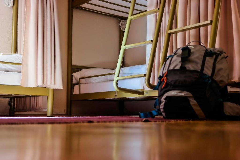 een rugzak op de vloer in een slaapkamer met stapelbedden bij ODA Hostel in Pristina