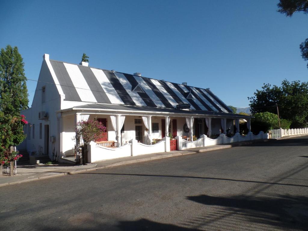 a white building with a black and white roof at Die Dorpshuis in Calitzdorp