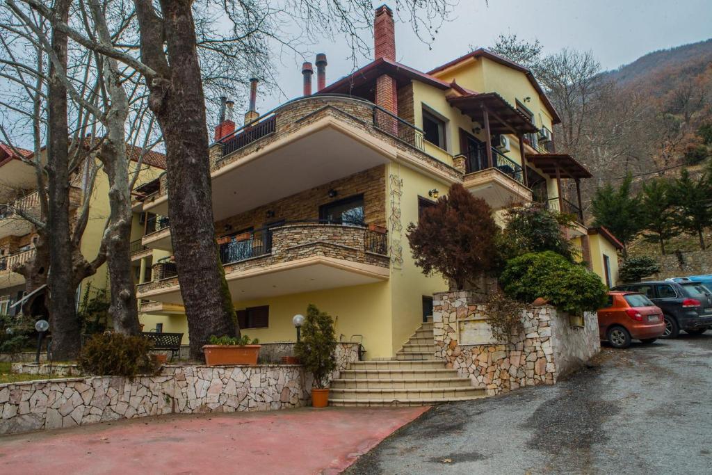 une maison jaune avec des escaliers devant elle dans l'établissement Nostos Hotel, à Kato Loutraki