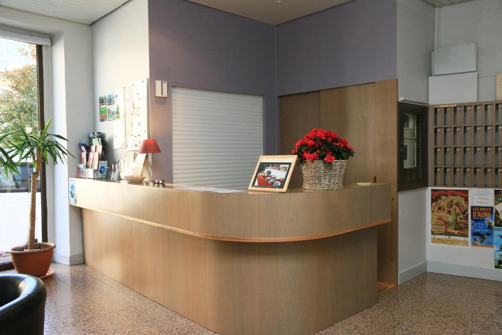 a lobby with a reception counter with flowers on it at Hôtel Panoramic in Luchon