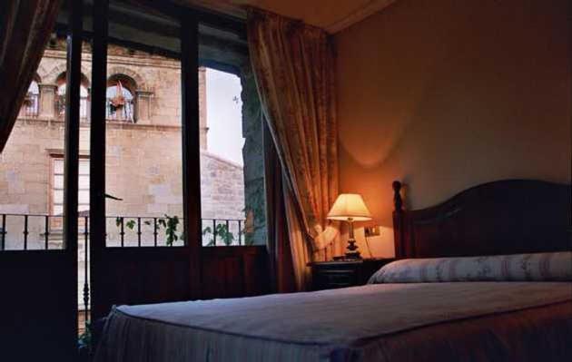 a bedroom with a bed and a large window at Hostal Las Coronas in Sos del Rey Católico