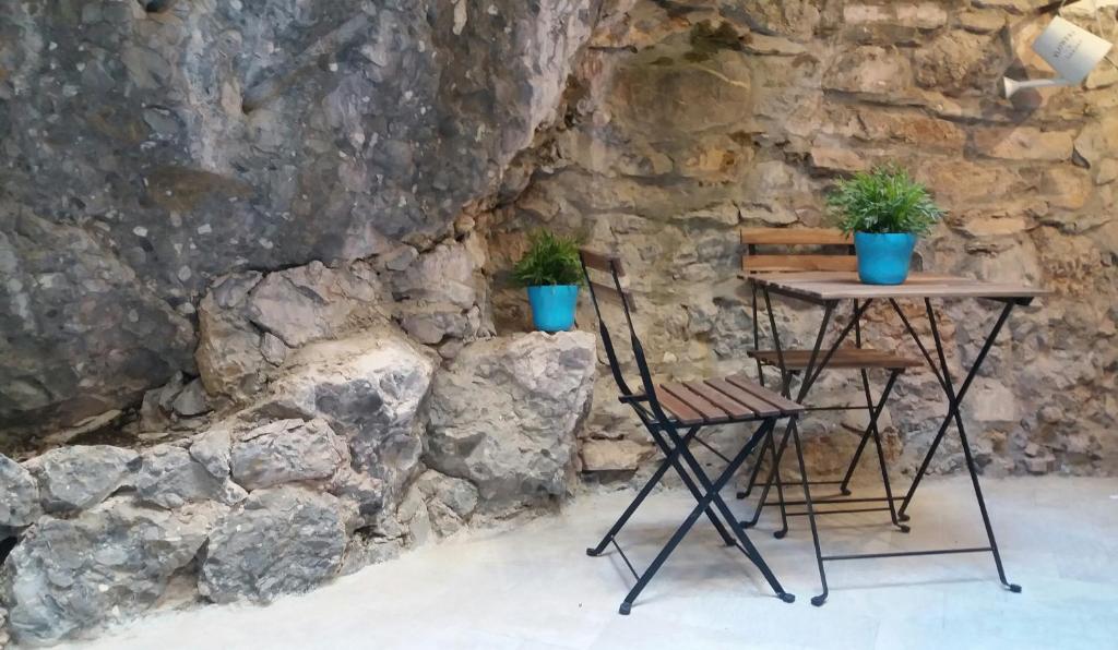 a table and chair next to a stone wall with two potted plants at Clara's House in Portofino