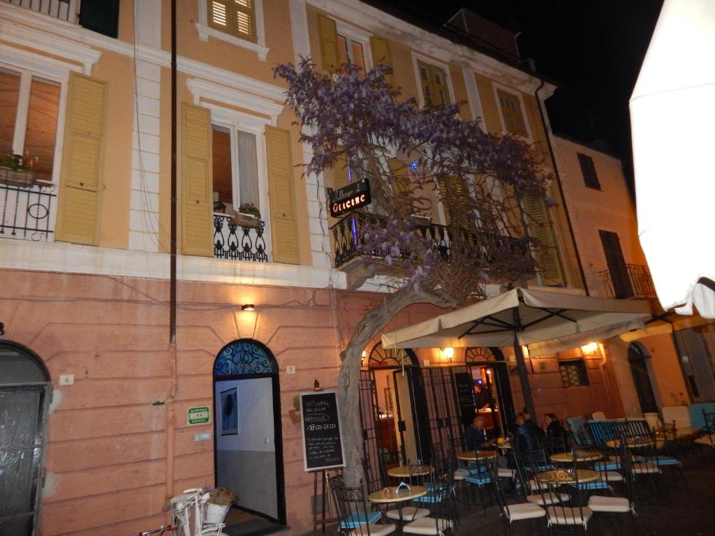 un bâtiment avec des tables et des chaises devant un bâtiment dans l'établissement Hotel Glicine, à Noli