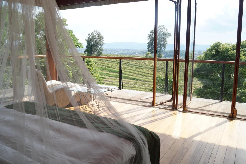 a bedroom with a bed and a large window at Aythaya Monte diVino Lodge in Taunggyi