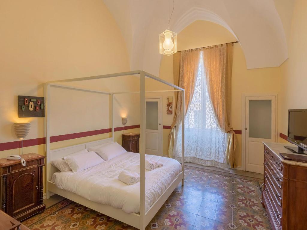 1 dormitorio con cama con dosel y TV en La Naca Della Taranta B&B, en Galatina