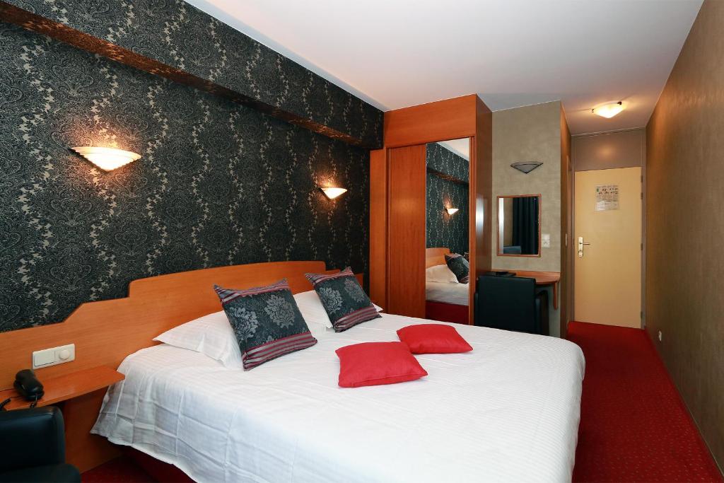- une chambre avec un grand lit blanc et des oreillers rouges dans l'établissement Hotel Figaro, à Knokke-Heist