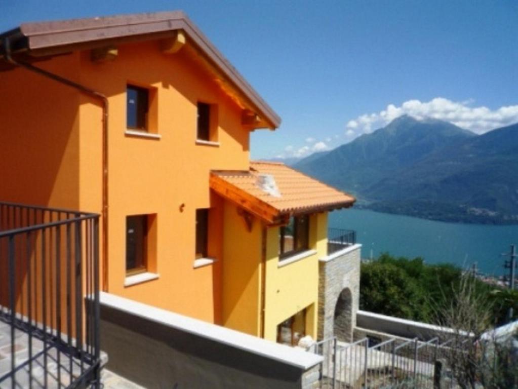 a yellow house with a view of a lake and mountains at Residence Borgo la Sorgente in Gravedona