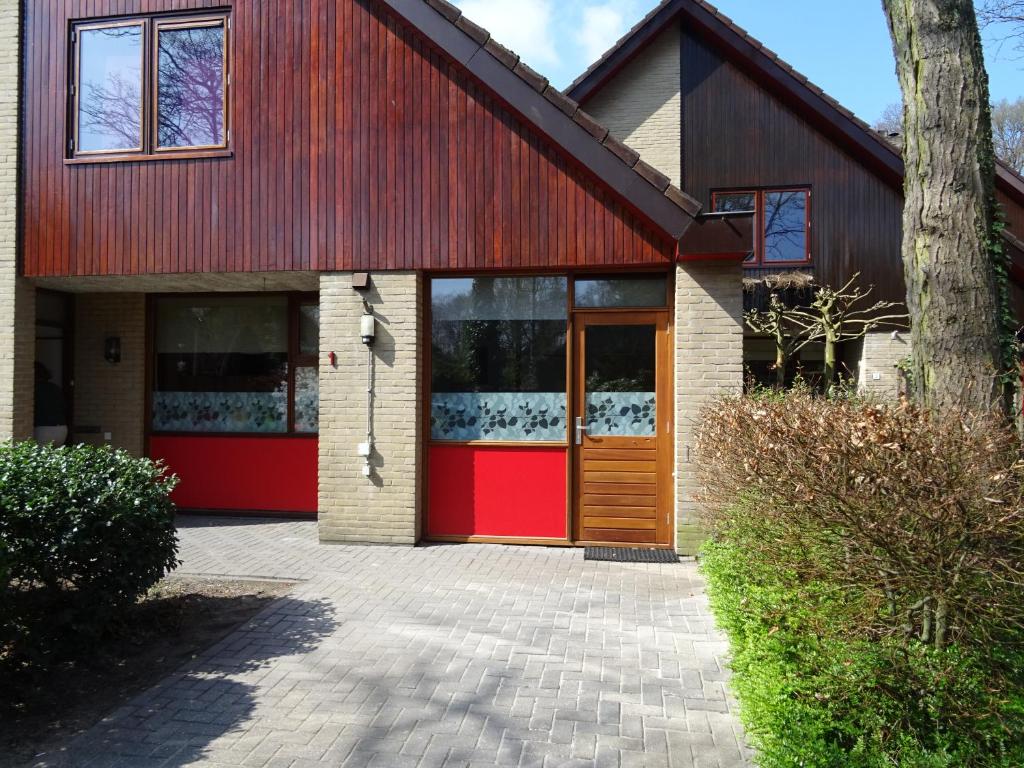 a house with a red door and a tree at Utrechtse Heuvelrug in Doorn