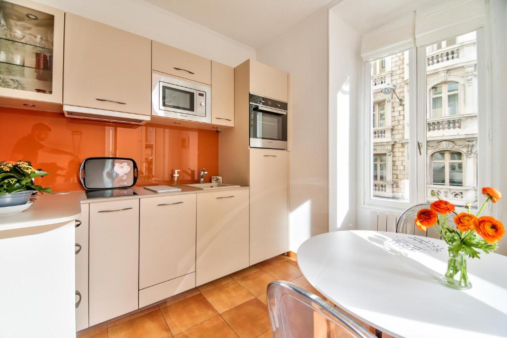 a kitchen with white cabinets and a table with flowers at L'Olivette in Nice