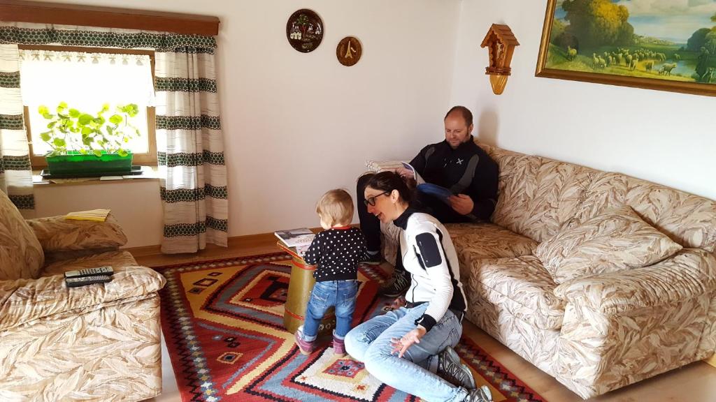 une femme et un homme assis dans un salon avec un enfant dans l'établissement Ospitalità Diffusa Laste Dolomites - Cèsa Murer, à Pallua