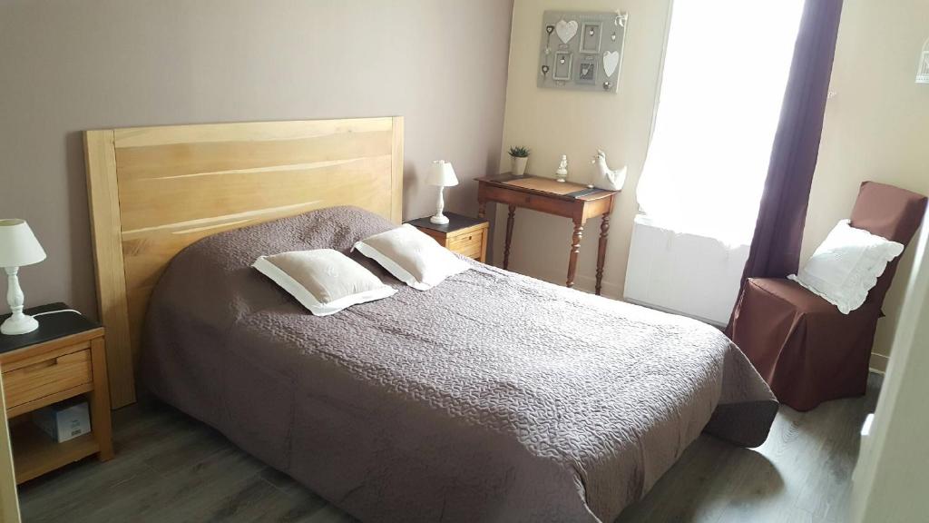 een slaapkamer met een bed met 2 kussens en een stoel bij Aux Cottages du port Honfleur in Honfleur