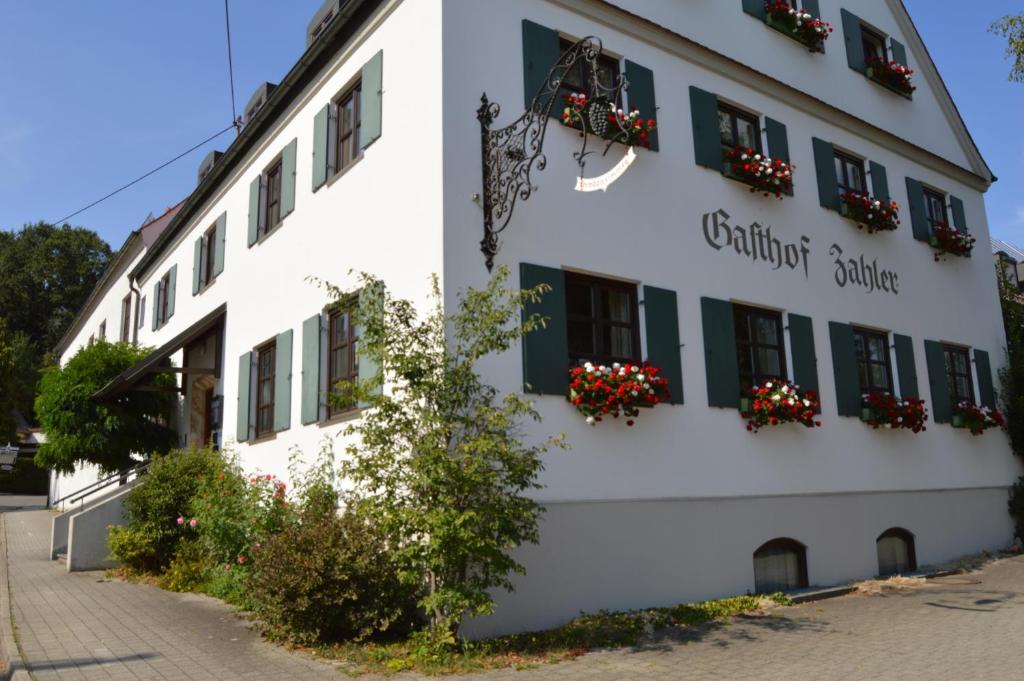 ein weißes Gebäude mit Blumen an den Fenstern in der Unterkunft Gasthof Zahler in Röfingen