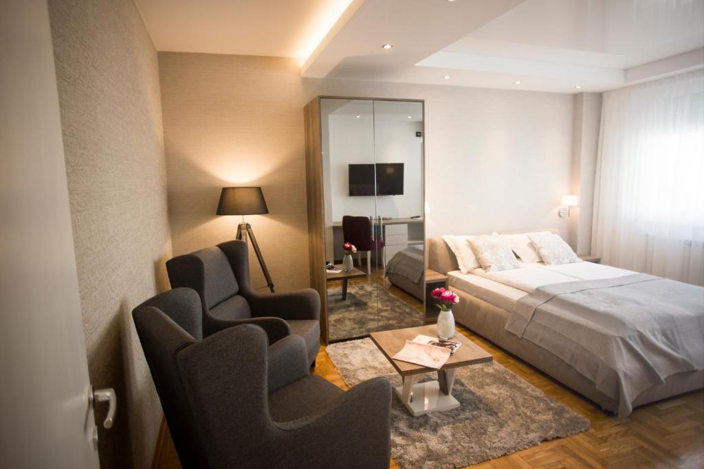a hotel room with a bed and two chairs at Dia Belgrade Arena Apartment in Belgrade