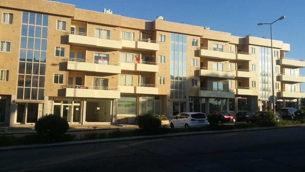 un gran edificio con coches estacionados frente a él en Orchidee Apartment, en Canedo