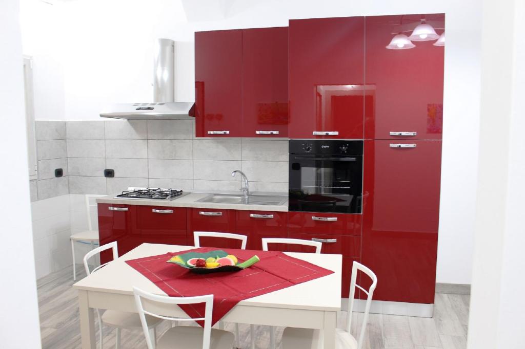 eine Küche mit roten Schränken und einem weißen Tisch in der Unterkunft Rosy's Apartments in Trappeto