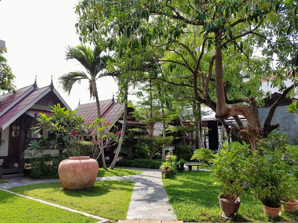 a garden with a large vase in front of a house at Niwas Ayutthaya in Phra Nakhon Si Ayutthaya