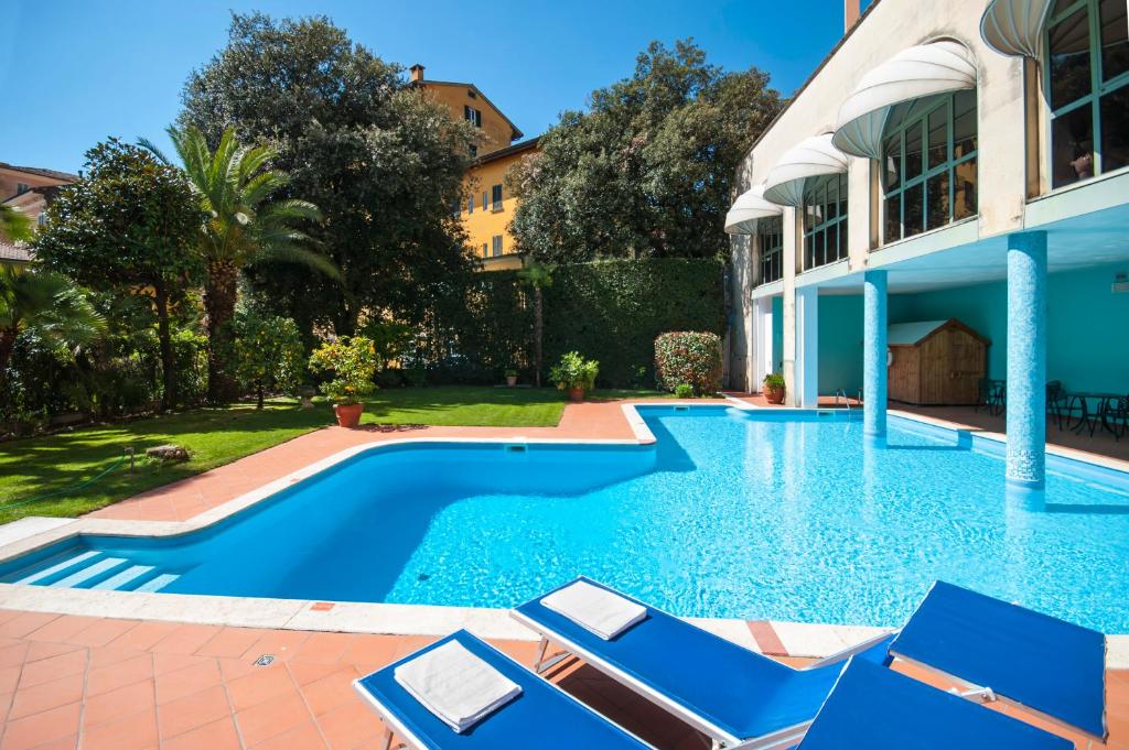 a swimming pool with blue chairs and a house at Hotel Settentrionale Esplanade in Montecatini Terme