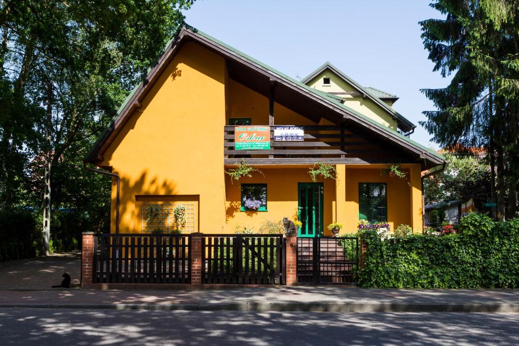 a yellow house with a fence in front of it at Dom Gościnny Oskar in Pobierowo