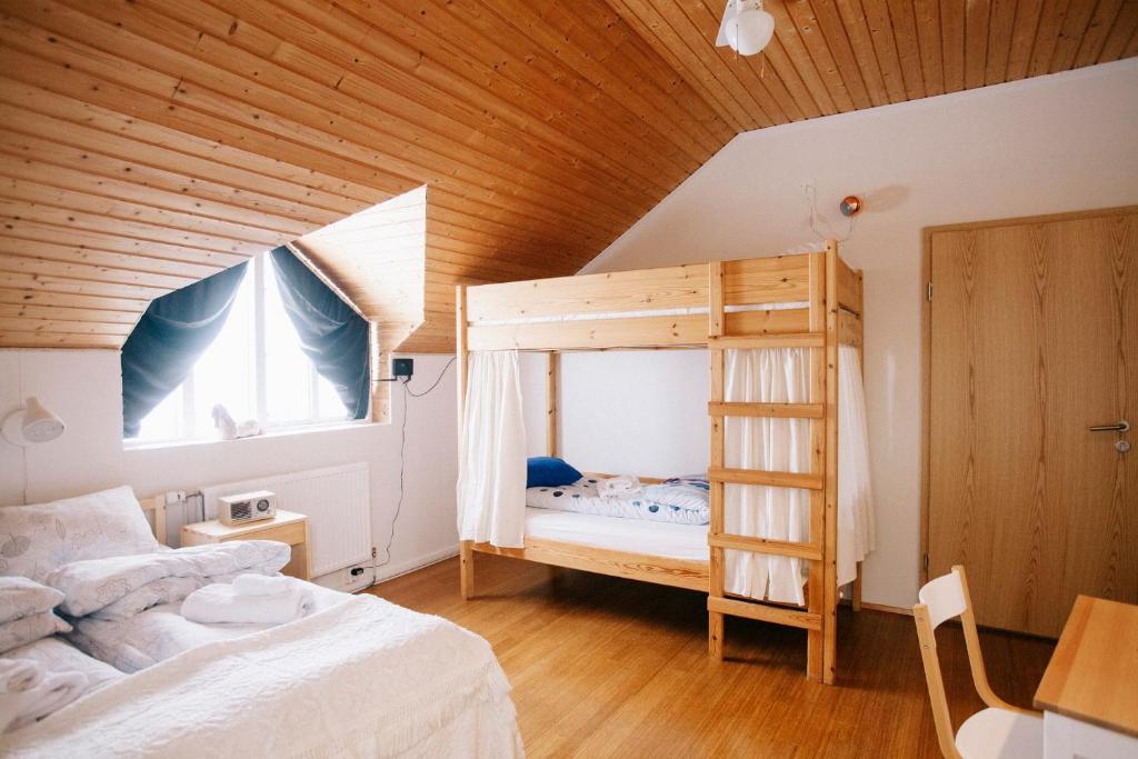 a bedroom with a bunk bed and a wooden ceiling at Skorrahestar in Neskaupstaður