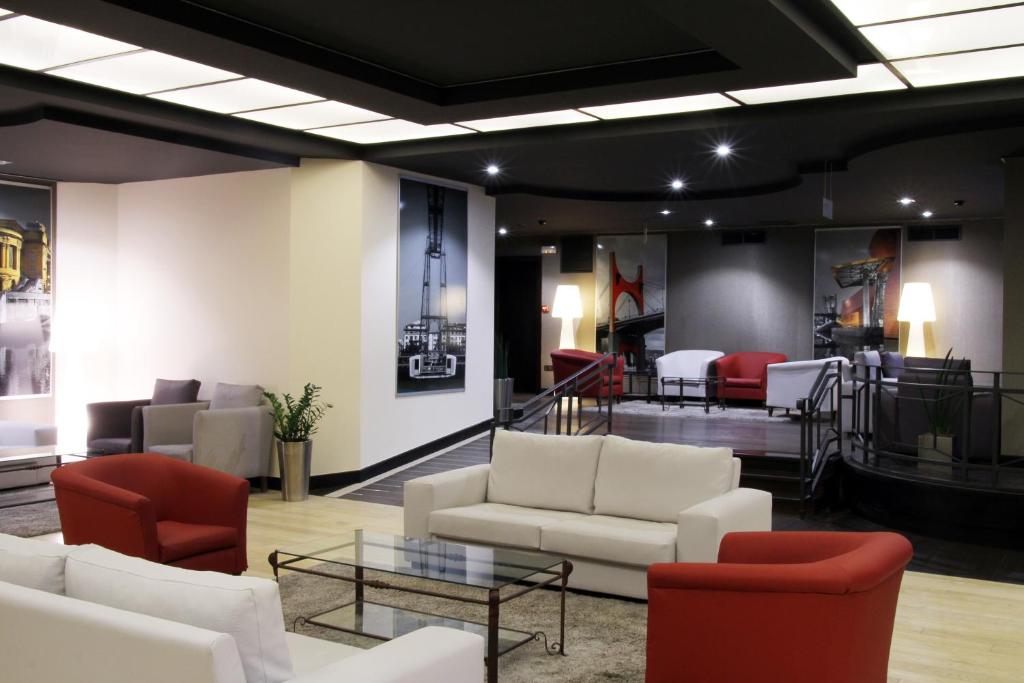 eine Lobby mit Sofas, Stühlen und einem Tisch in der Unterkunft Hotel Conde Duque Bilbao in Bilbao