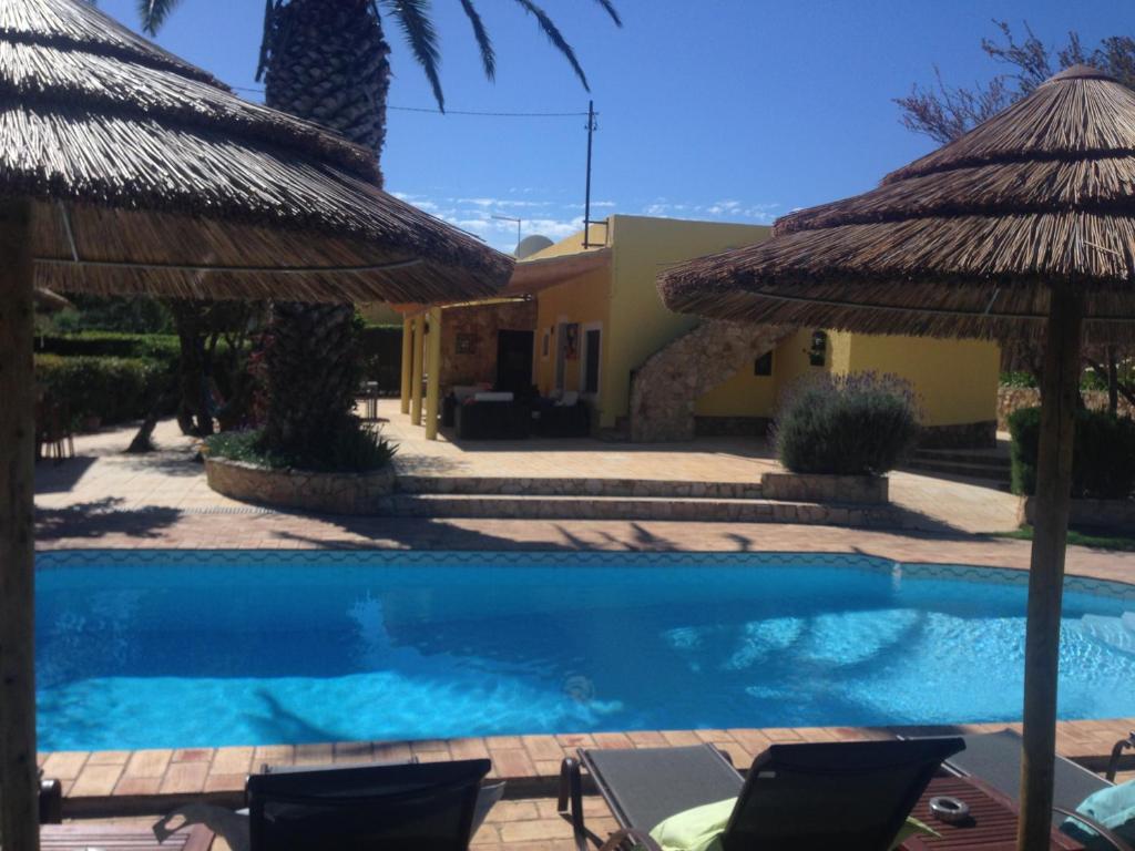 einen Pool mit 2 Stühlen und Sonnenschirmen in der Unterkunft Casa Paula Villas - Private Heated Pool for Each House in Lagos