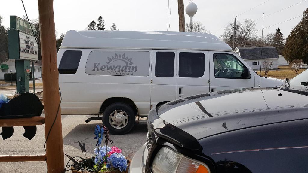 a white van is parked in a parking lot at Bear Cove Inn in Saint Ignace