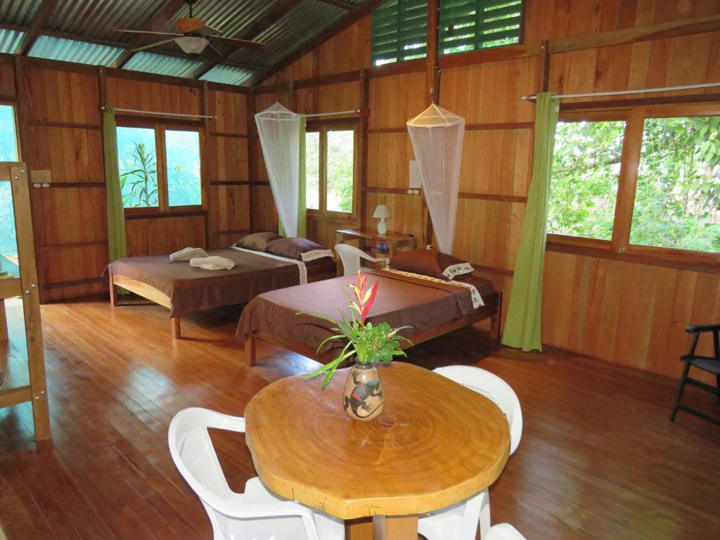 a living room with a table and chairs and windows at Cabañas Bajo Bosque Drake in Drake
