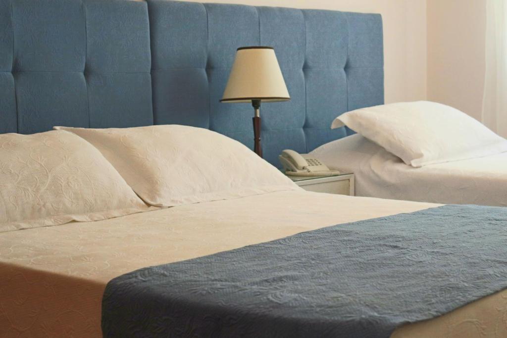 a bed with a blue headboard next to a phone at Hotel San Martin in Punta del Este