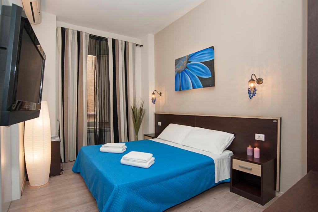 a bedroom with a blue bed and a television at Flowerome in Rome
