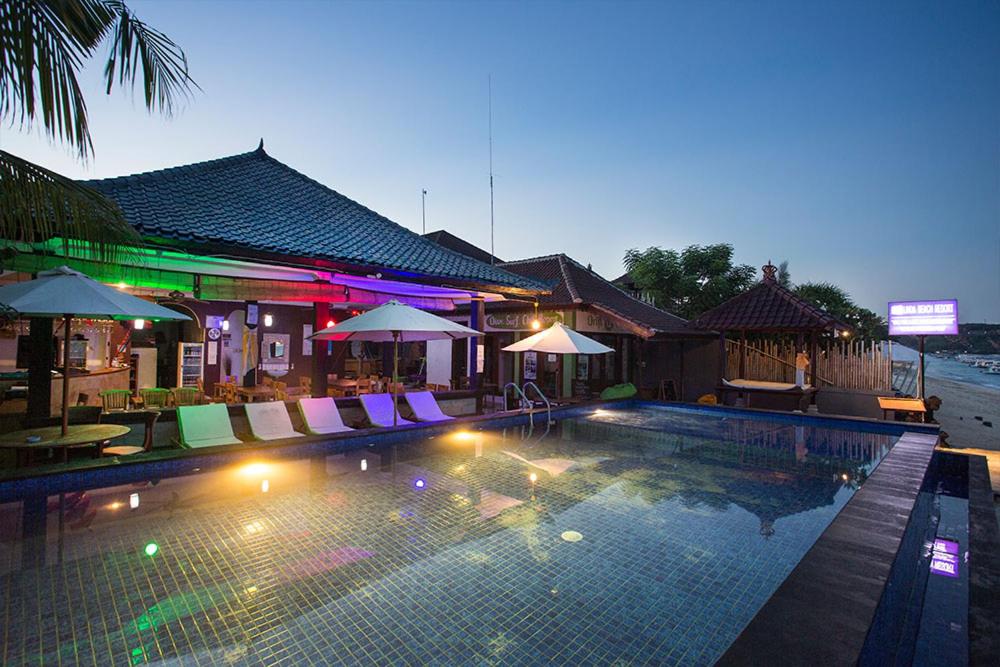a swimming pool with chairs and umbrellas at night at Linda Beach Hotel in Nusa Lembongan