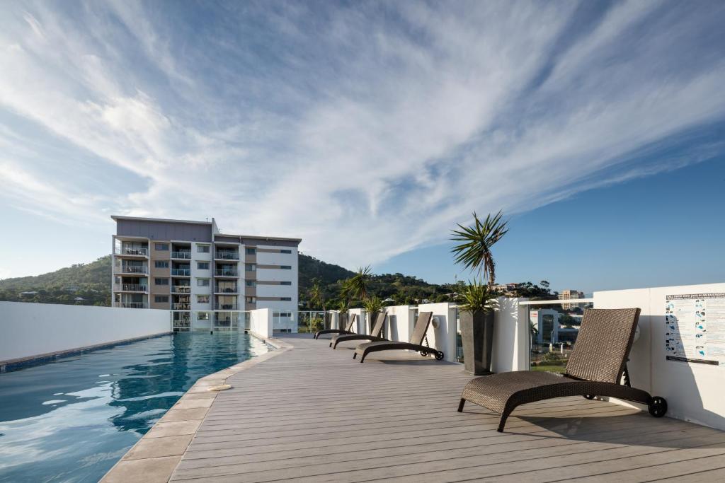 a deck with chairs and a swimming pool on a building at Central Holborn Apartments in Townsville