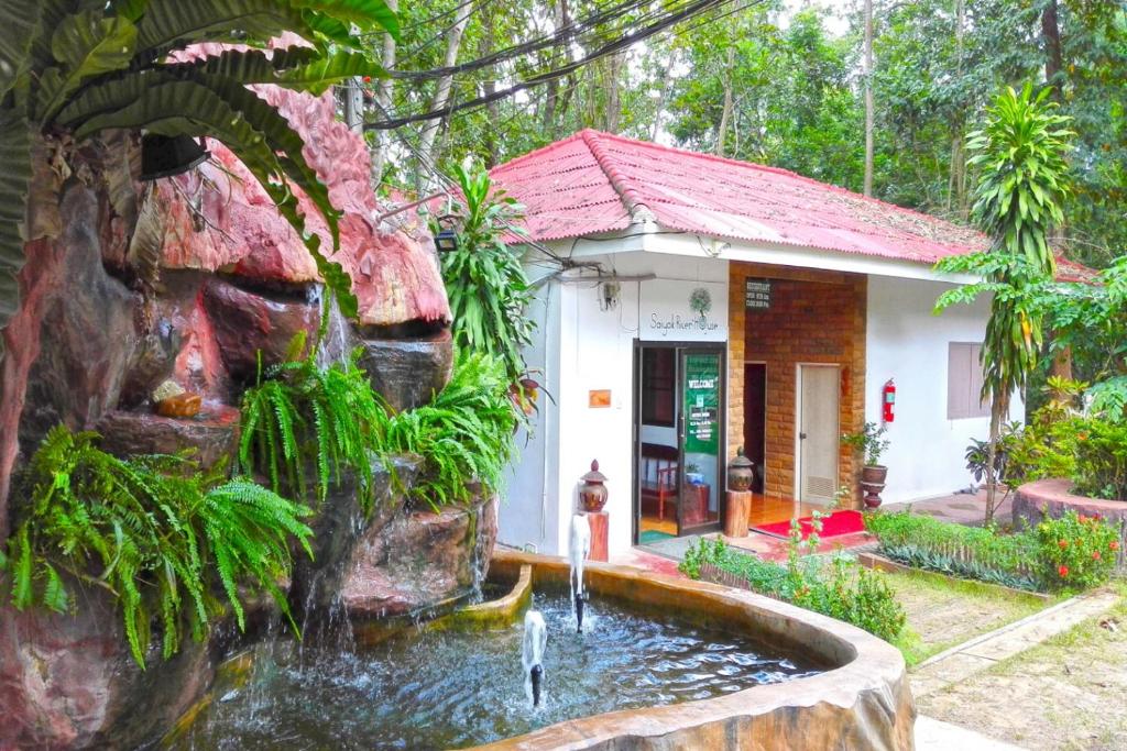 a house with a pond in front of a building at Saiyok River House in Sai Yok