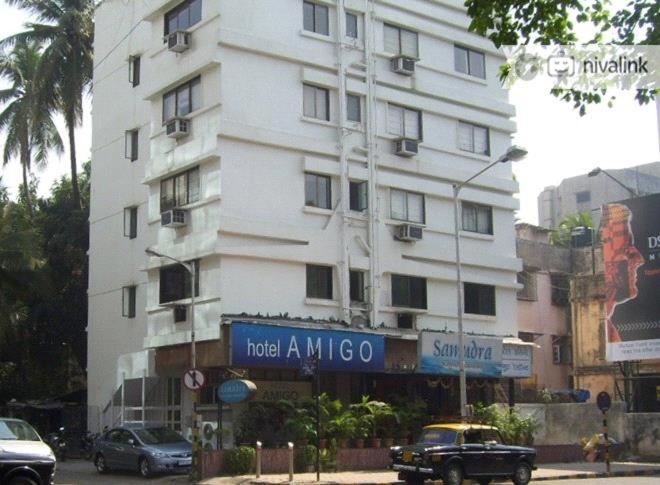 - un grand bâtiment blanc avec un panneau devant dans l'établissement Hotel Amigo, à Mumbai
