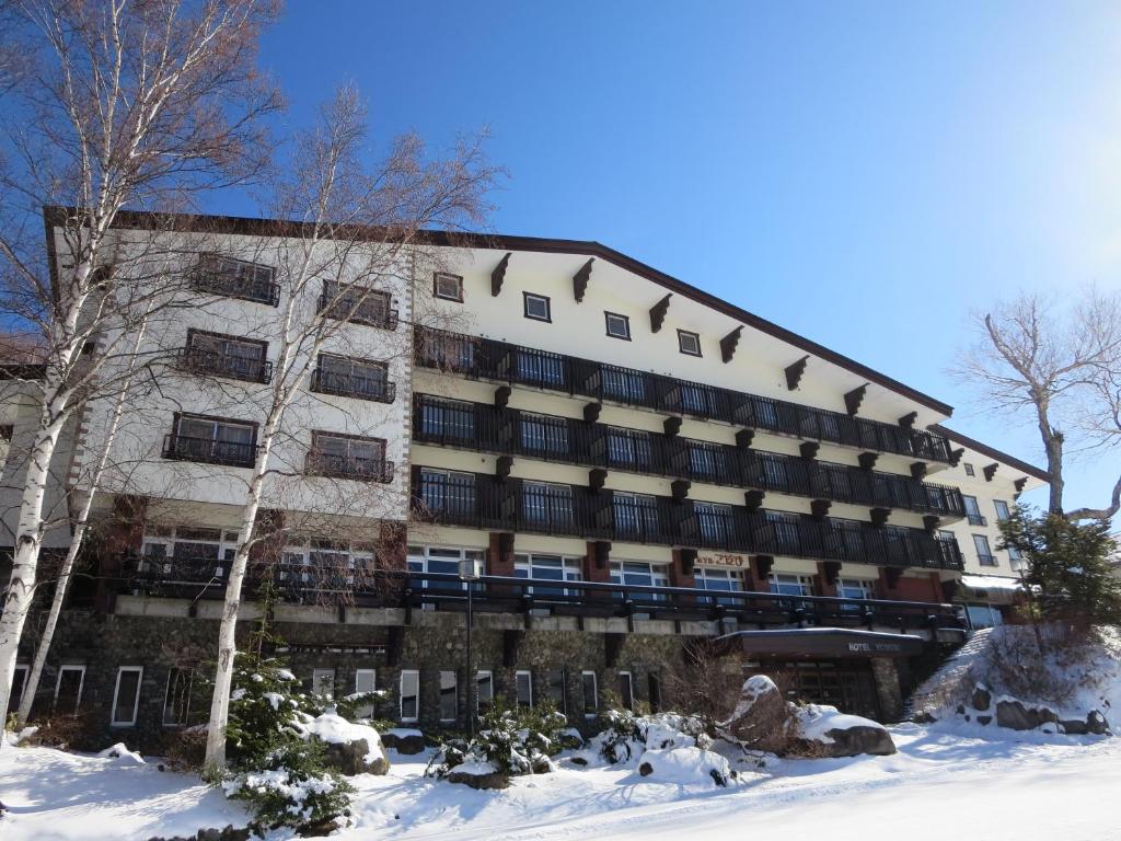 a large building with snow in front of it at Hotel Kodama in Yamanouchi