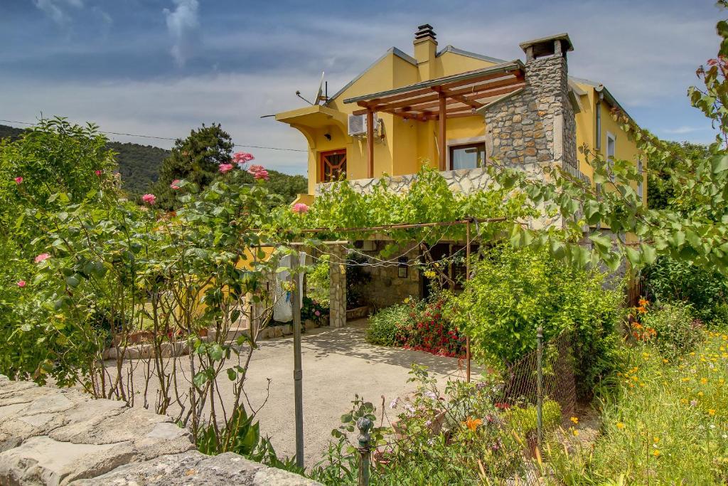 a yellow house with a garden in front of it at Apartman Astrid in Veli Lošinj