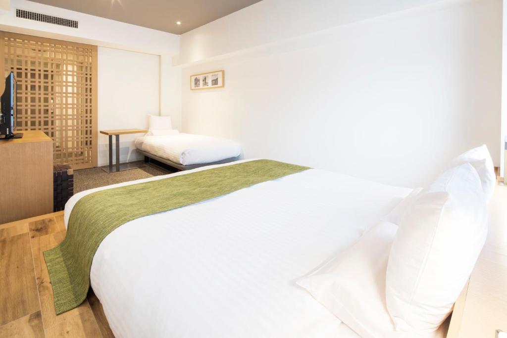 a bedroom with a large white bed and a television at HOTEL MYSTAYS PREMIER Omori in Tokyo