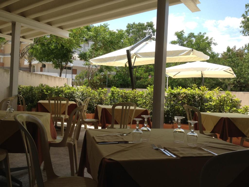 restauracja ze stołami i parasolami na patio w obiekcie Hotel Turismo w mieście Metaponto