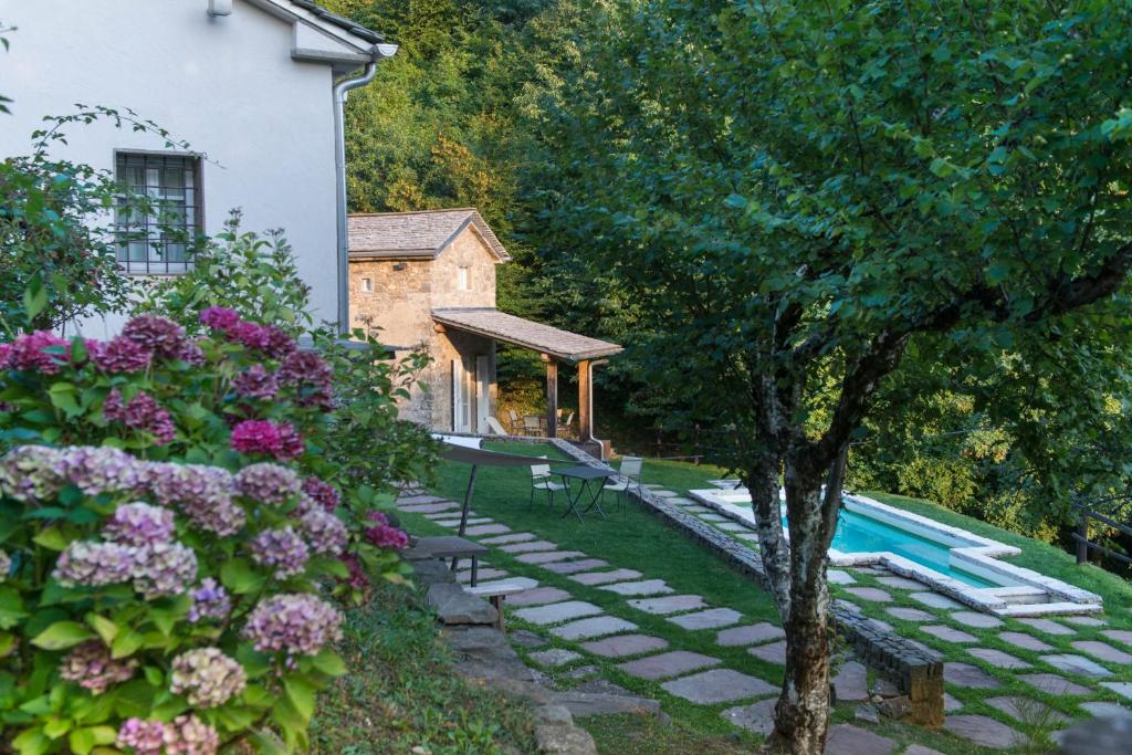 un jardín con piscina y una casa en SASSO AL MELO - Apartments, en Cutigliano