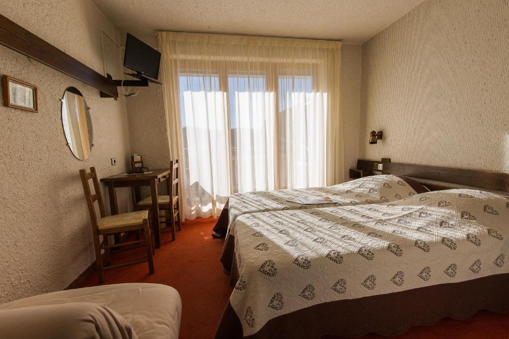 a hotel room with two beds and a window at Hotel Le Tetras in Notre-Dame-de-Bellecombe