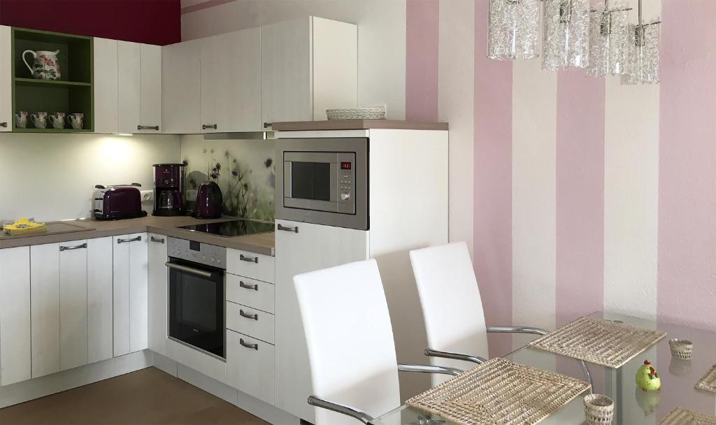 eine Küche mit weißen Geräten und rosa und weißen Streifen in der Unterkunft Apartment Romantik Flair in Prerow