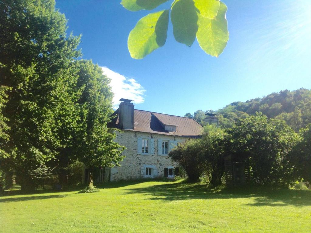 ein altes Haus auf einem grünen Feld mit Bäumen in der Unterkunft B&B Au Moulin 1771 in Monein